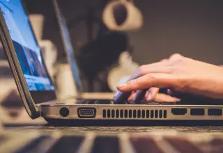 Computer user typing on a laptop whilst attending a webinar